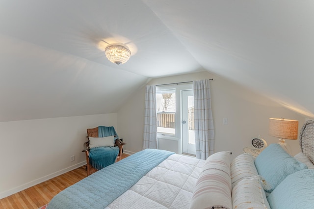 bedroom with light hardwood / wood-style flooring, vaulted ceiling, and access to exterior