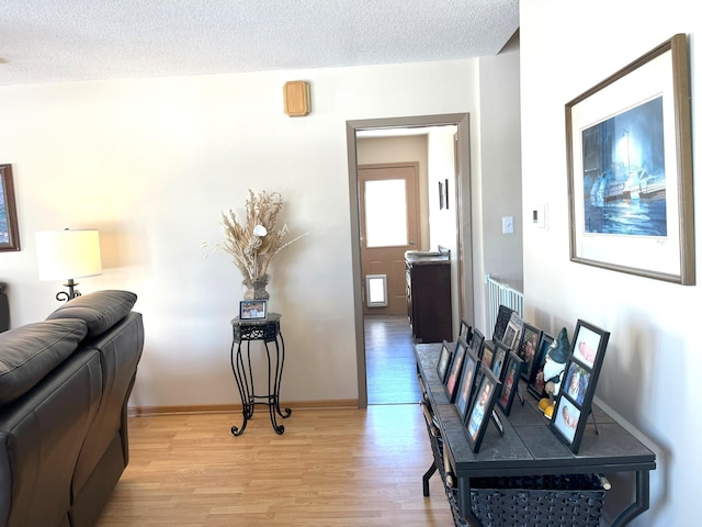 hallway with light hardwood / wood-style floors and a textured ceiling