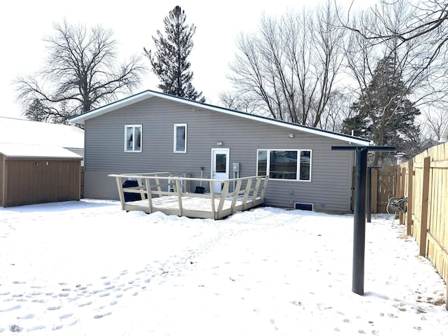 snow covered back of property featuring a wooden deck