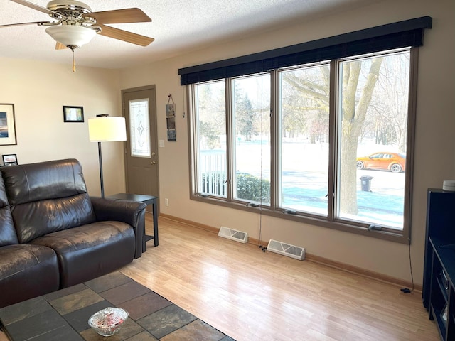 living room featuring ceiling fan, wood-type flooring, and a textured ceiling