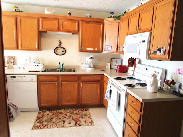 kitchen featuring sink, a textured ceiling, and white appliances