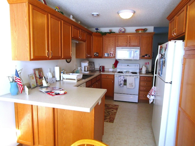 kitchen featuring sink, white appliances, kitchen peninsula, and a textured ceiling