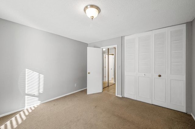 unfurnished bedroom with a textured ceiling, a closet, and light colored carpet