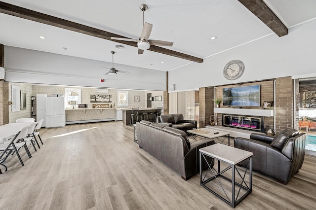 living room featuring ceiling fan, light hardwood / wood-style flooring, and beamed ceiling