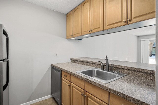 kitchen featuring light tile patterned floors, baseboards, a sink, appliances with stainless steel finishes, and a textured ceiling