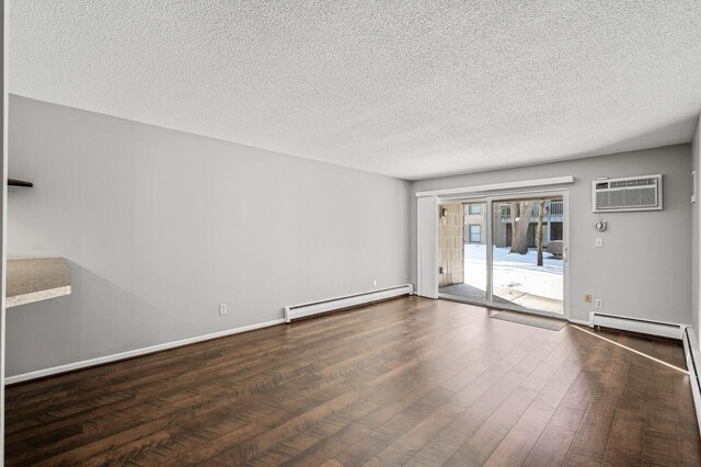 empty room with a wall mounted AC, baseboard heating, baseboards, a textured ceiling, and wood-type flooring