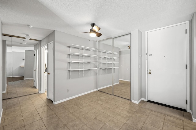unfurnished bedroom featuring a closet, a textured ceiling, baseboards, and ceiling fan