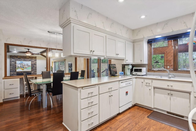 kitchen featuring white cabinetry, kitchen peninsula, sink, white dishwasher, and dark wood-type flooring