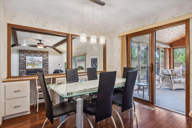 dining area with ceiling fan, vaulted ceiling with beams, and dark hardwood / wood-style flooring