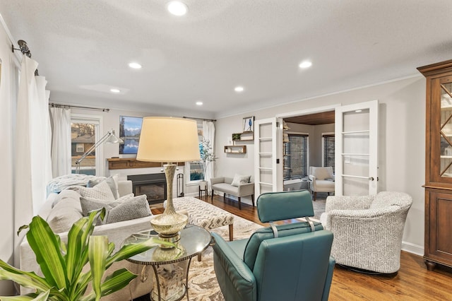 living room featuring hardwood / wood-style flooring, crown molding, french doors, and a textured ceiling