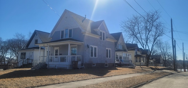 view of side of property with roof with shingles and a porch