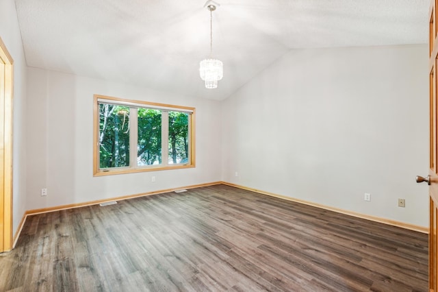 empty room with vaulted ceiling, a chandelier, and wood-type flooring