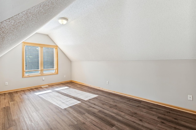 additional living space featuring hardwood / wood-style flooring, a textured ceiling, and lofted ceiling