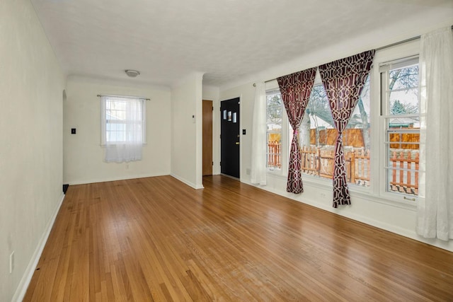 unfurnished room featuring a wealth of natural light, baseboards, and wood finished floors