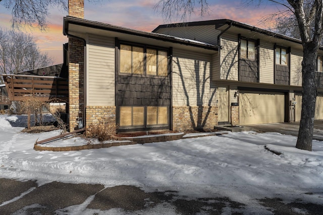 exterior space with brick siding, a chimney, and an attached garage