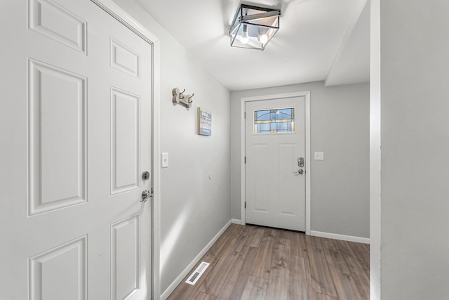 doorway to outside with light wood-type flooring, visible vents, and baseboards