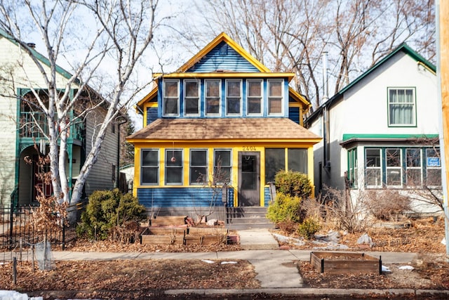 view of front of property featuring a sunroom and a shingled roof