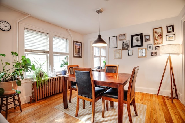 dining area featuring light wood-style flooring, radiator heating unit, and baseboards