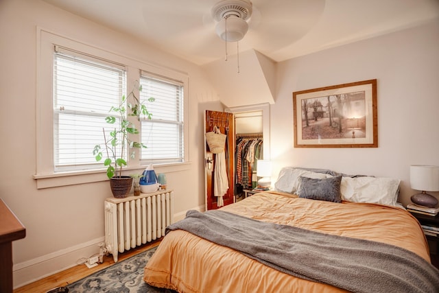 bedroom featuring a closet, radiator, baseboards, and wood finished floors