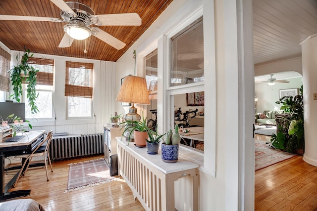 sunroom / solarium featuring arched walkways, wooden ceiling, radiator heating unit, and ceiling fan