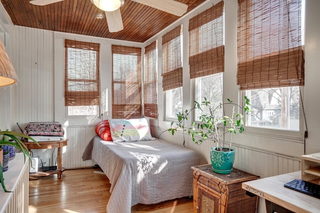 bedroom featuring wood ceiling, wood finished floors, and a wainscoted wall