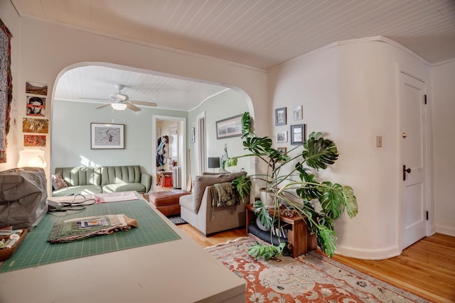 living area featuring ornamental molding, a ceiling fan, arched walkways, light wood-style floors, and wooden ceiling