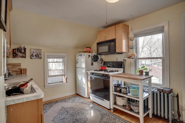 kitchen with light brown cabinetry, plenty of natural light, white appliances, and vaulted ceiling