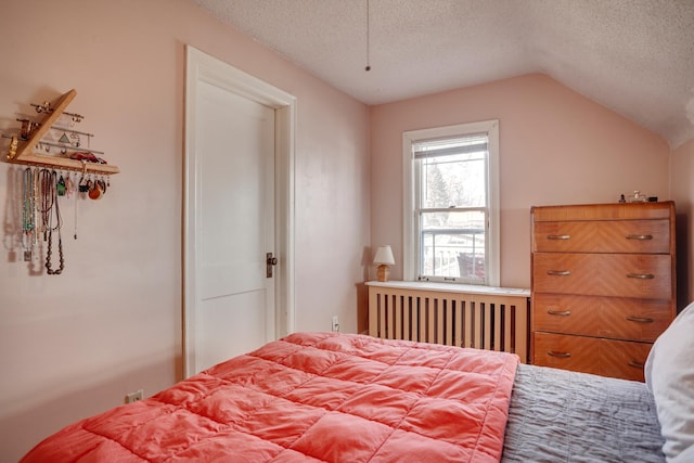 bedroom with a textured ceiling, radiator heating unit, and vaulted ceiling