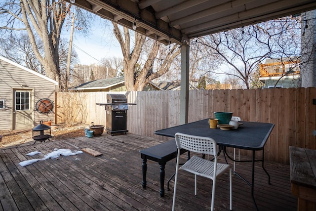 deck with outdoor dining space, a grill, and fence