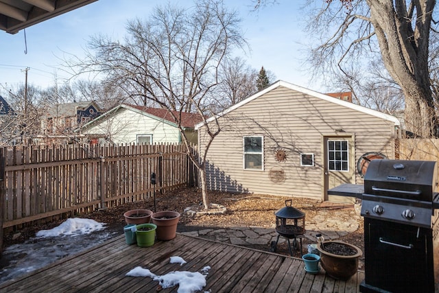 deck with area for grilling, a fire pit, and a fenced backyard