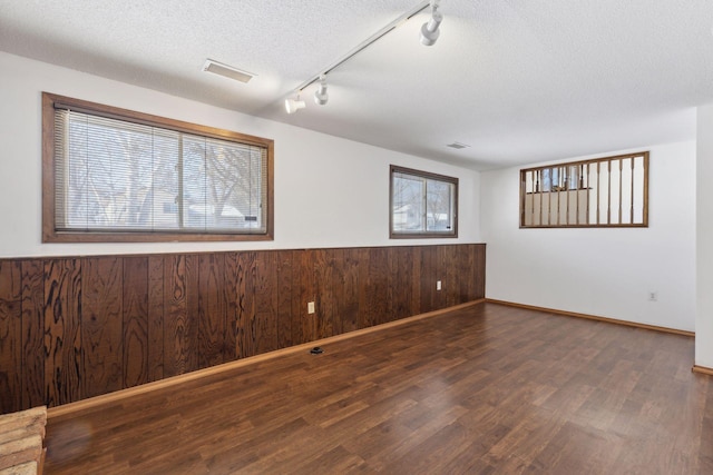 unfurnished room with dark hardwood / wood-style flooring, wood walls, and a textured ceiling