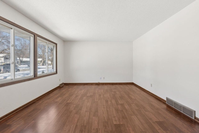 unfurnished room with dark wood-type flooring and a textured ceiling