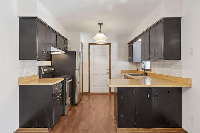 kitchen featuring hanging light fixtures, stainless steel range with electric cooktop, sink, and kitchen peninsula