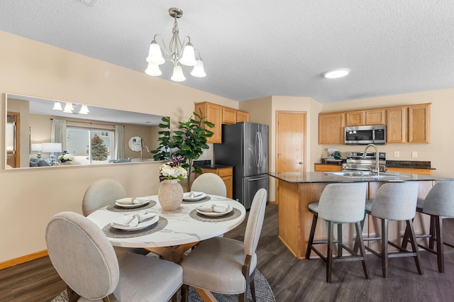 dining area featuring sink, a textured ceiling, an inviting chandelier, and dark hardwood / wood-style flooring