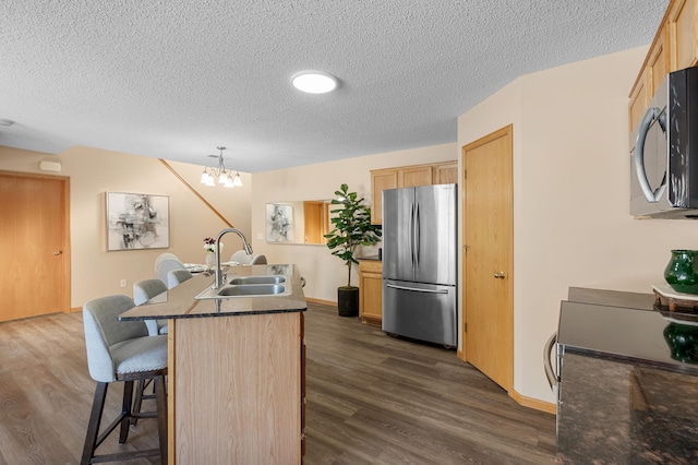 kitchen featuring decorative light fixtures, stainless steel appliances, light brown cabinetry, and sink