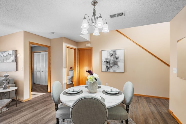 dining room with dark hardwood / wood-style flooring, a textured ceiling, and a notable chandelier