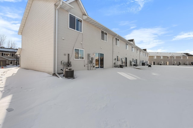 snow covered rear of property with cooling unit