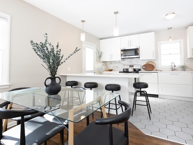 kitchen with decorative light fixtures, stainless steel appliances, white cabinets, and plenty of natural light