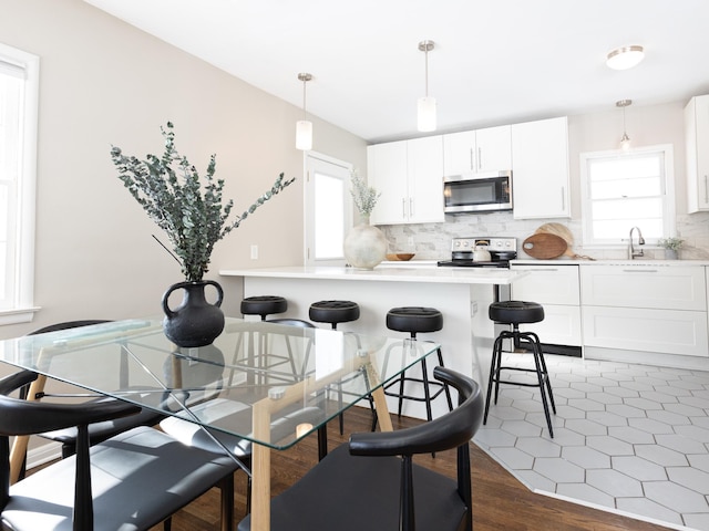 kitchen with plenty of natural light, appliances with stainless steel finishes, white cabinetry, and pendant lighting