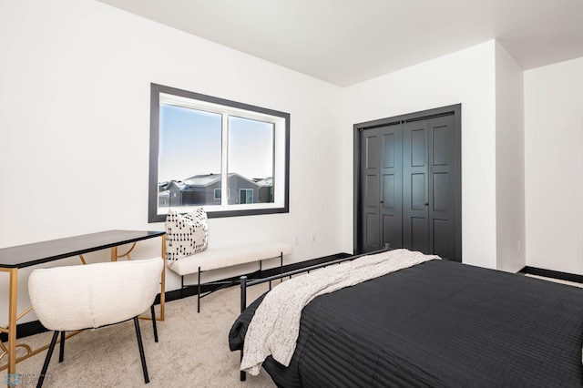 bedroom with a closet, light carpet, and baseboards