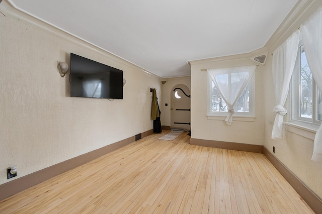 unfurnished living room with hardwood / wood-style floors and crown molding