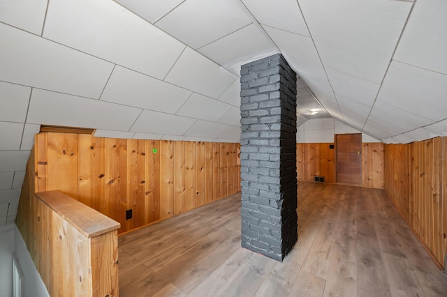 additional living space with light hardwood / wood-style flooring, wooden walls, and lofted ceiling