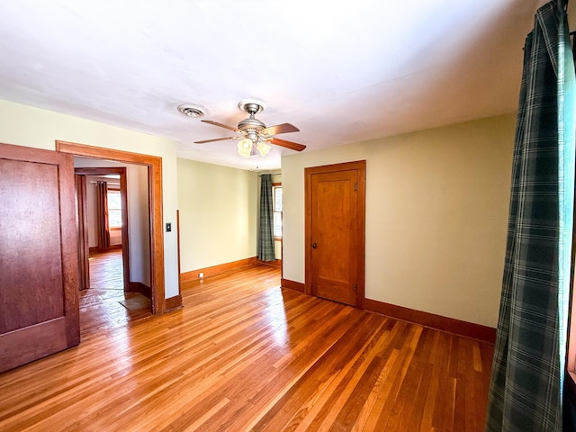 unfurnished room featuring visible vents, baseboards, light wood-style flooring, and a ceiling fan