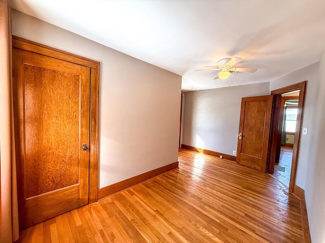 empty room with a ceiling fan, baseboards, and light wood-type flooring