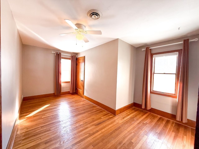 spare room with light wood-style flooring, baseboards, visible vents, and ceiling fan