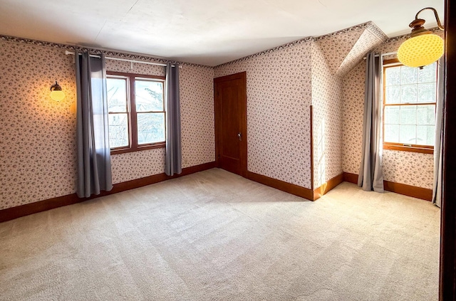 spare room with baseboards, light colored carpet, and wallpapered walls