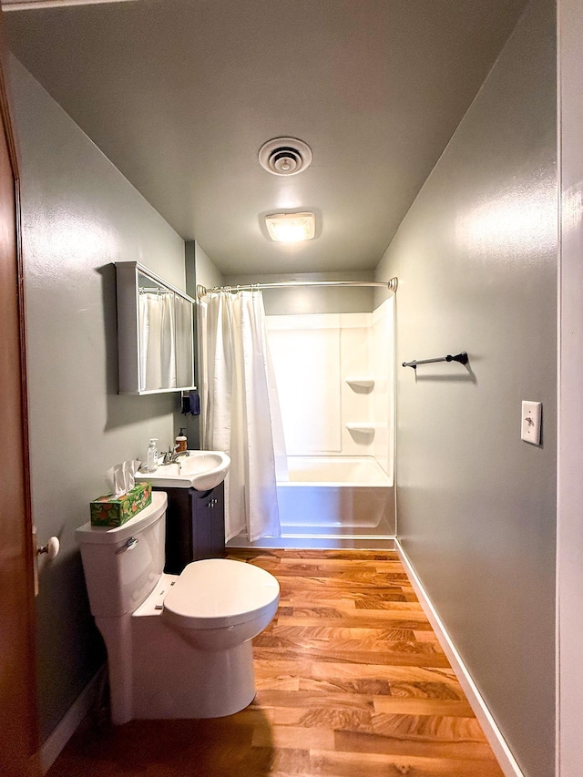 full bathroom featuring wood finished floors, visible vents, a sink, shower / bath combo with shower curtain, and toilet