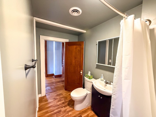 bathroom with vanity, toilet, wood finished floors, and visible vents