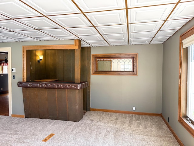 carpeted spare room featuring baseboards and an ornate ceiling