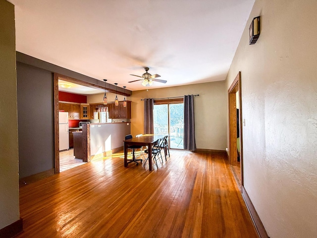 unfurnished dining area featuring light wood finished floors, baseboards, and ceiling fan